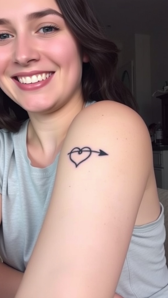 A smiling person showcasing a fine-line heart tattoo with an arrow on their arm.